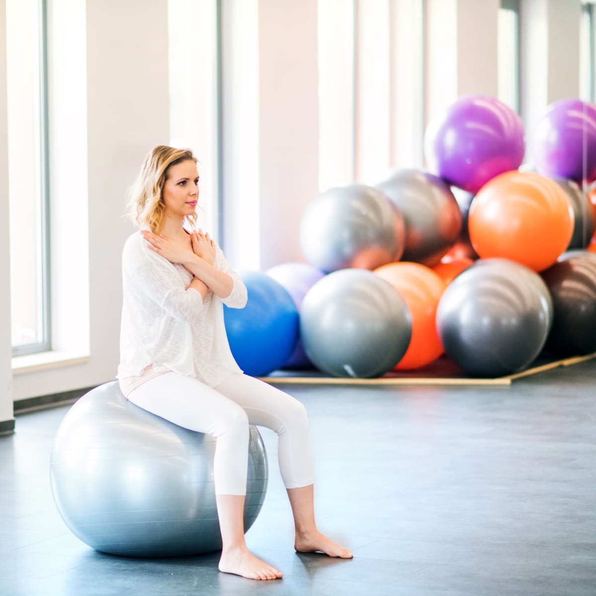 Young woman doing exercise with a fitball in a gym.